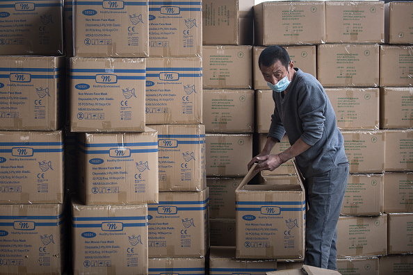 Un ouvrier transporte des caisses de manutention avec des masques pour l'exportation au port à conteneurs de Yangluo sur le fleuve Yangtze le 12 avril 2020 à Wuhan, dans la province de Hubei, en Chine. (Photo by Getty Images)