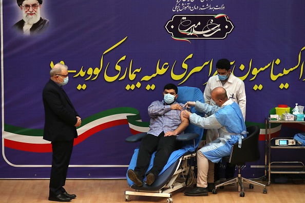 -Le ministre iranien de la Santé Saeed Namaki regarde son fils Parsa qui reçoit le premier vaccin à l'hôpital Imam Khomeini de la capitale Téhéran, le 9 février 2021. Photo par Atta Kenare / AFP via Getty Images.