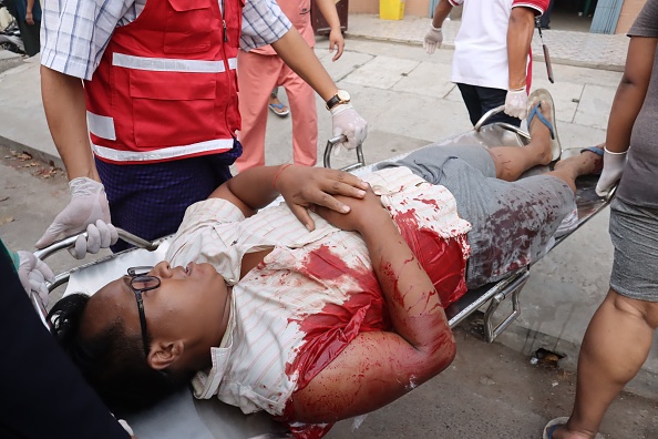 -Un homme blessé est transporté après que les forces de sécurité ont ouvert le feu sur des manifestants, à Mandalay le 20 février 2021. Photo de STR / AFP via Getty Images.