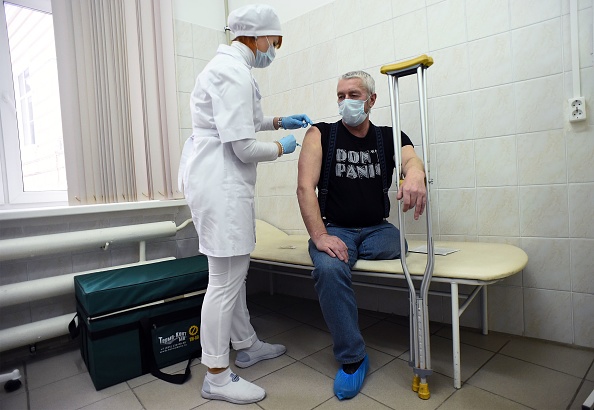 Un travailleur de la santé administre à un homme une dose du vaccin russe Spoutnik V (Gam-COVID-Vac) contre le Covid-19, dans un centre de vaccination à Saint-Pétersbourg, le 21 février 2021, alors que la Russie lance une campagne de vaccination de masse contre le Covid-19 pour les sans-abri.  (OLGA MALTSEVA/AFP via Getty Images)