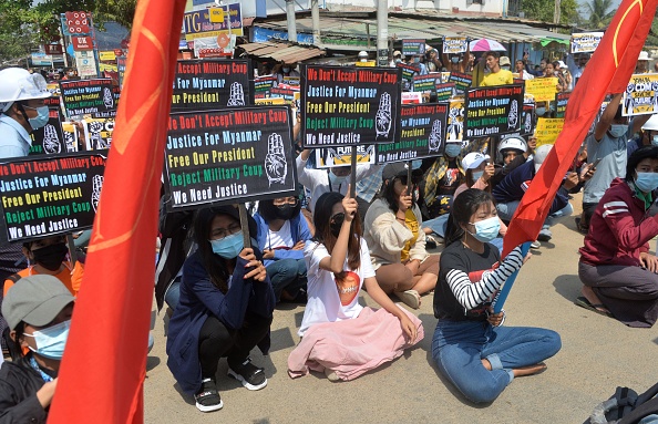 -Des manifestants tiennent des pancartes lors d'une manifestation en Birmanie le 26 février 2021. Photo de STR / AFP via Getty Images.