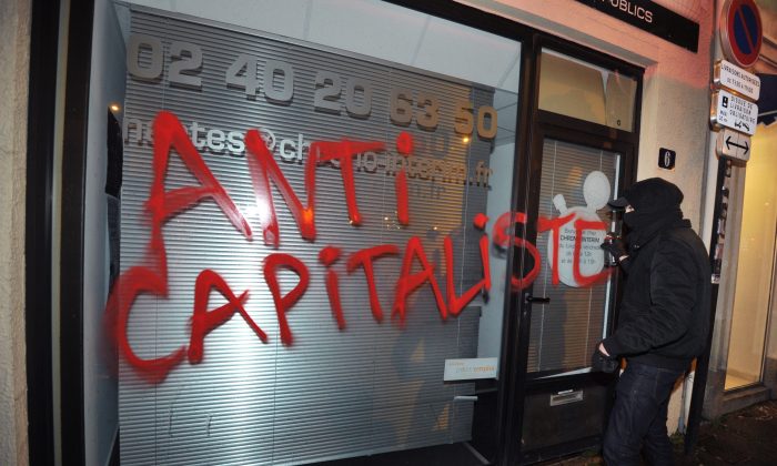 Un membre d’Antifa vandalise une vitrine à Nantes, France, le 14 février 2014. (FRANK PERRY/AFP/Getty Images)