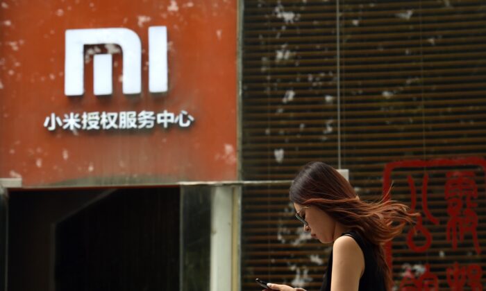 Une femme passe devant un logo Xiaomi devant un centre de services Xiaomi à Pékin le 5 août 2015. (Greg Baker/AFP via Getty Images)