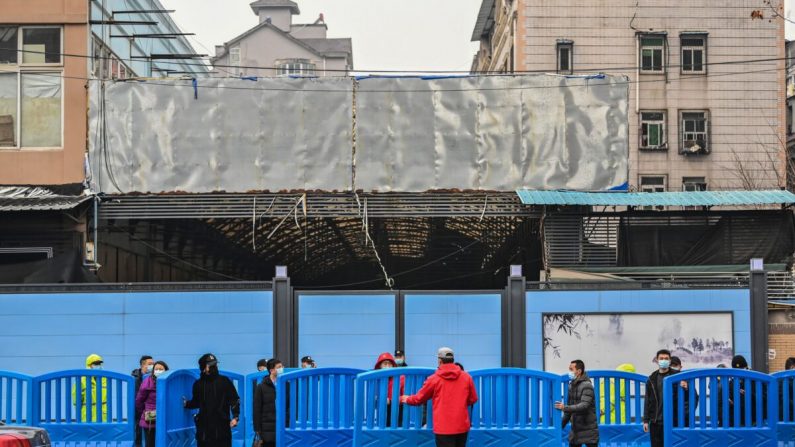 Des travailleurs placent des barrières à l'extérieur du marché de fruits de mer fermé de Huanan Seafood lors d'une visite de membres de l'équipe de l'OMS, qui enquête sur les origines du coronavirus Covid-19, à Wuhan, dans la province centrale du Hubei en Chine, le 31 janvier 2021. (Hector Retamal/AFP via Getty Images)