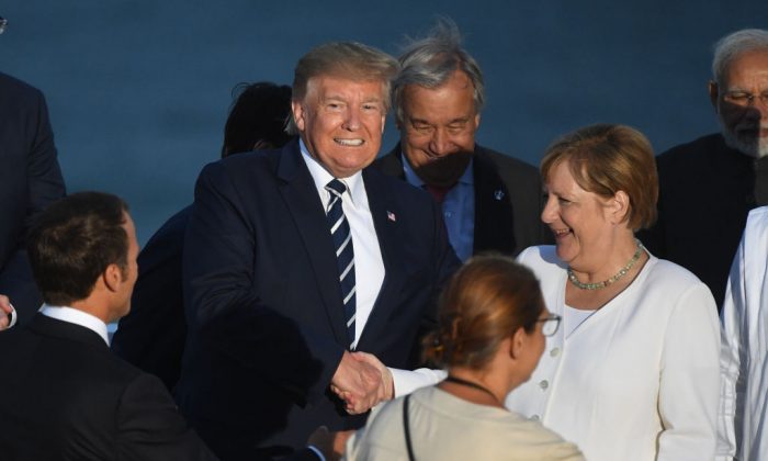 Le président américain Donald Trump serre la main de la chancelière allemande Angela Merkel devant le président français Emmanuel Macron lors du sommet annuel du G7 à Biarritz, en France, le 25 août 2019. (Andrew Parsons - Pool/Getty Images)