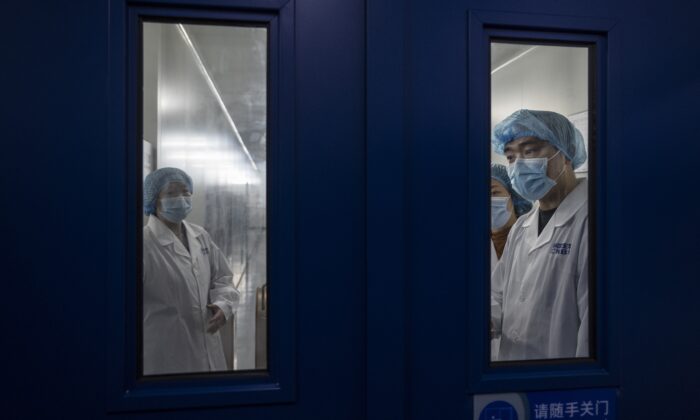 Des employés attendent d'ouvrir la porte sécurisée dans la zone de conditionnement du vaccin inactivé contre le SRAS-CoV-2 de Sinopharm CNBG destiné au Covid-19 lors d'une visite des médias organisée par le Bureau d'information du Conseil d'État à Pékin le 26 février 2021. (Kevin Frayer/Getty Images)