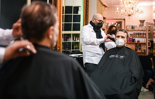 -Le coiffeur Marco Trapani coupe les cheveux d'un client à la réouverture de son salon de coiffure fermé en raison de la pandémie à Dortmund, dans l'ouest de l'Allemagne, le 1er mars 2021. Photo de Ina Fassbender / AFP via Getty Images.