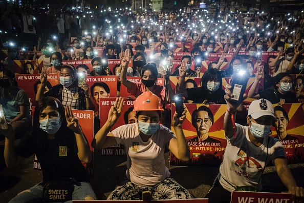 -Des manifestants brandissent le salut à trois doigts et des pancartes avec l'image du chef civil birman détenu Aung San Suu Kyi. Photo par STR / AFP via Getty Images.