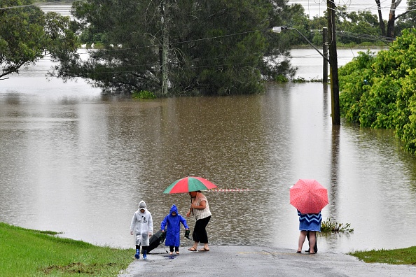 -Une famille revient après avoir regardé une route coupée par les eaux de crue dans la banlieue de Richmond le 22 mars 2021. Photo par Saeed Khan / AFP via Getty Images.