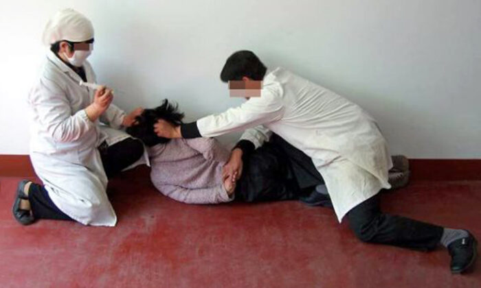 Reconstitution d'une scène où on injecte de force à un victime des médicaments psychiatriques. Les abus psychiatriques sont une méthode courante de persécution en Chine pour contraindre les gens à abandonner leur foi. (Minghui.org)