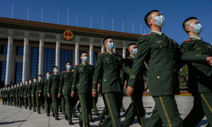 Des soldats chinois de l'Armée populaire de libération portent des masques de protection alors qu'ils marchent après une cérémonie marquant le 70e anniversaire de l'entrée de la Chine dans la guerre de Corée, au Grand Hall du Peuple à Beijing, en Chine, le 23 octobre 2020. (Kevin Frayer/Getty Images)