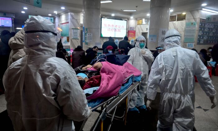 Le personnel médical portant des vêtements de protection contre un coronavirus précédemment inconnu arrive avec un patient à l'hôpital de la Croix-Rouge de Wuhan, en Chine, le 25 janvier 2020. (Hector Retamal/AFP via Getty Images)