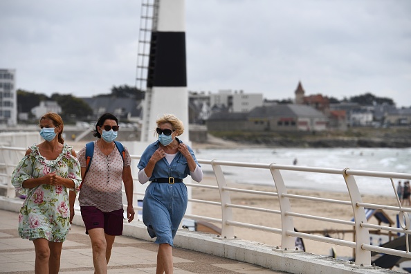 Des femmes portant un masque marchent le long du front de mer le 27 juillet 2020 à Quiberon, dans l'ouest de la France. (FRED TANNEAU/AFP via Getty Images)