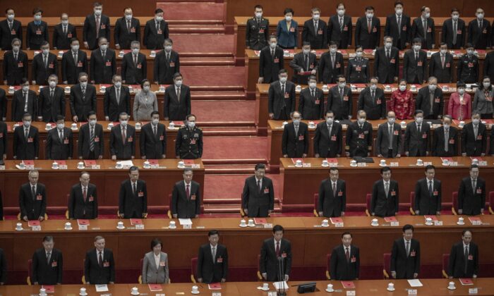 Le dirigeant chinois Xi Jinping (au centre) et les législateurs chinois se lèvent pour l'hymne national lors de la session de clôture de la conférence de la législature chinoise qui fait office de parlement-tampon, au Grand palais du Peuple à Pékin, le 11 mars 2021. (Kevin Frayer/Getty Images)