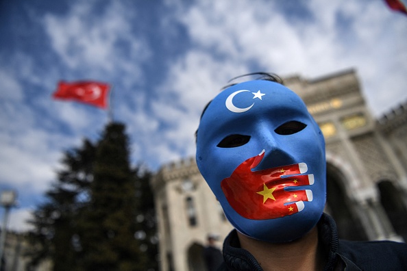 -Un manifestant porte un masque peint aux couleurs du drapeau du Turkestan oriental le 1er avril 2021 à Istanbul. Photo par Ozan Kose / AFP via Getty Images.