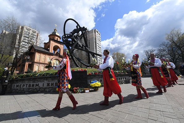 -Des personnes en costumes traditionnels ukrainiens portent des fleurs au mémorial de Tchernobyl à Kiev, le 26 avril 2021. Photo de Sergei SUPINSKY / AFP via Getty Images.