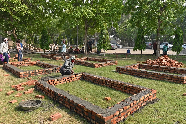 -Des travailleurs construisent des plates-formes pour des bûchers funéraires dans les locaux d'un crématorium à New Delhi le 27 avril 2021. Photo de SAJJAD HUSSAIN / AFP via Getty Images.