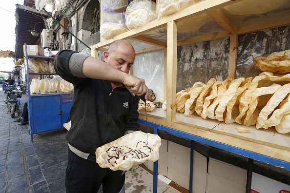 -Un vendeur syrien répand de la mélasse de raisin sur un dessert traditionnel appelé "al-Naaem", couramment servi pendant le mois du Ramadan, à Damas le 28 avril 2021. Photo par Louai Beshara / AFP via Getty Images.