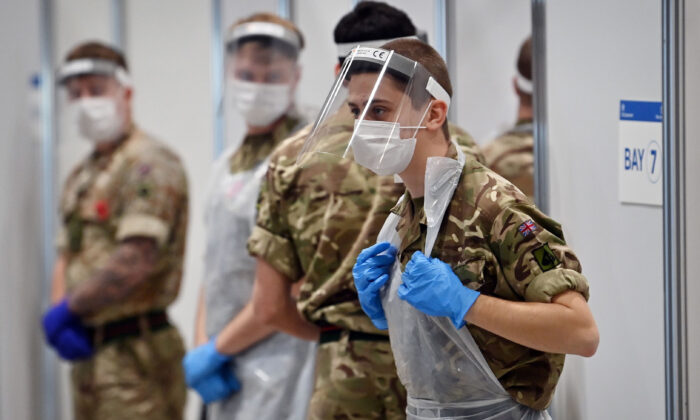 Des soldats portant un EPI complet sous forme d'écrans faciaux, de gants, de masques et de bavoirs attendent de participer au dépistage du virus du PCC dans un centre de dépistage rapide situé dans le centre d'exposition de Liverpool, en Angleterre, le 11 novembre 2020 (Paul Ellis/AFP via Getty Images).