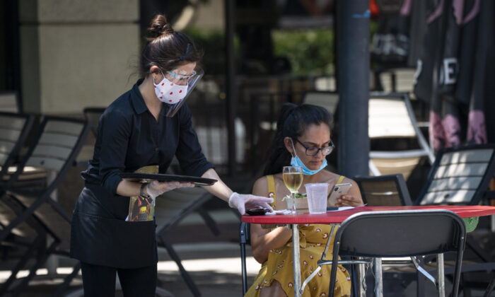 Une serveuse de Raku, un restaurant asiatique de Bethesda, porte un masque de protection pour servir les clients à l'extérieur dans le cadre de la pandémie de coronavirus à Bethesda, dans le Maryland, le 12 juin 2020. (Sarah Silbiger/Getty Images)