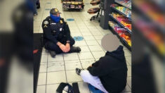 Une photo montre un aimable policier assis à terre avec un homme en crise de santé mentale dans une station-service