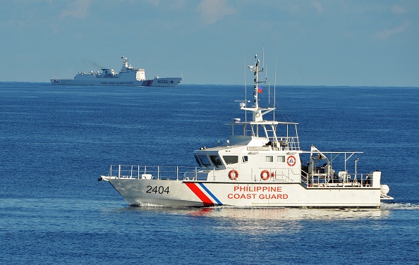 -Un navire des garde-côtes des Philippines passe devant un navire des garde-côtes chinois. Photo par Ted Aljibe / AFP via Getty Images.