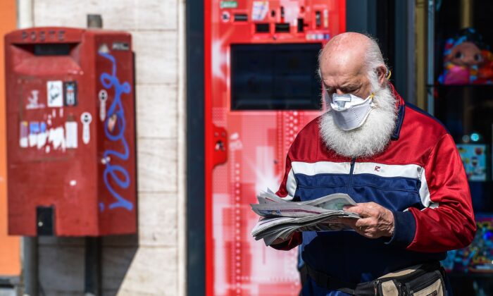 Un résident portant un masque facial sort d'un magasin après avoir acheté un journal à Treviolo, en Italie, le 9 avril 2020. (Miguel Medina/AFP via Getty Images)