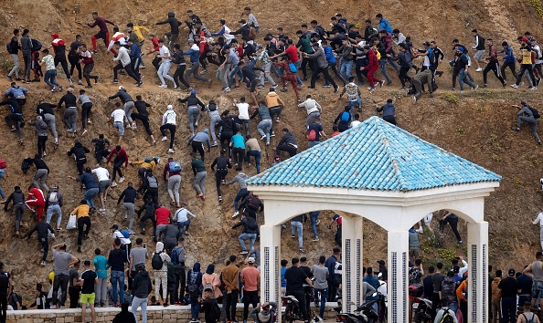 Les migrants évitent la police marocaine alors qu'ils tentent d'atteindre la frontière entre le Maroc et l'enclave espagnole de Ceuta le 18 mai 2021 à Fnideq. (Photo : FADEL SENNA/AFP via Getty Images)