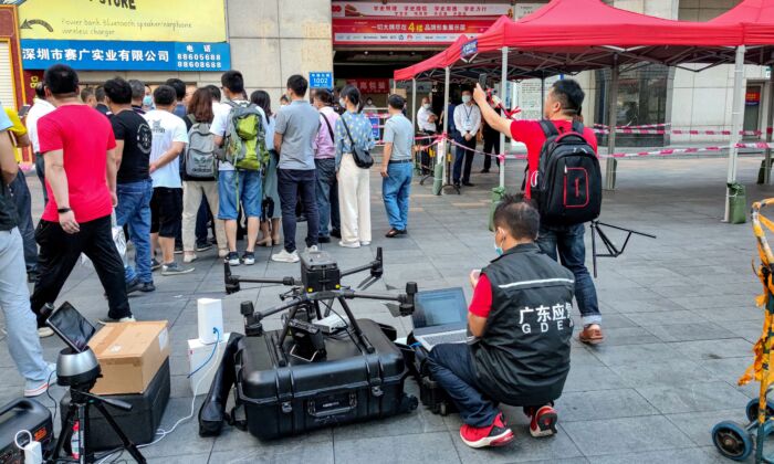 Un membre du personnel du département de gestion des urgences (devant) travaille avec un drone devant le SEG Plaza à Shenzhen, en Chine, le 19 mai 2021, le lendemain du jour où le bâtiment a déclenché une panique générale lorsqu'il s'est mis à trembler et a été évacué. (AFP via Getty Images)