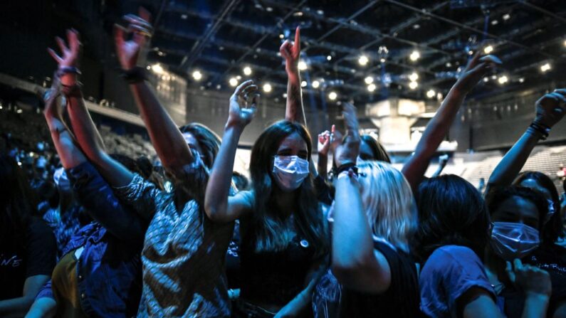 Des personnes applaudissent lors d'un concert du DJ français Etienne de Crecy et du groupe pop Indochine, visant à tester scientifiquement le niveau de sécurité vis-à-vis de l'infection Covid-19 et les possibilités de réouverture des événements en direct dans le contexte de la pandémie, à l'AccorHotels Arena de Paris, le 29 mai 2021. (STEPHANE DE SAKUTIN/AFP via Getty Images)