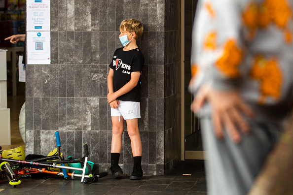 Un enfant attend à l'extérieur d'un magasin où les clients doivent s'identifier à l'aide d'un QR code en Australie, début janvier 2021. (Jenny Evans/Getty Images)