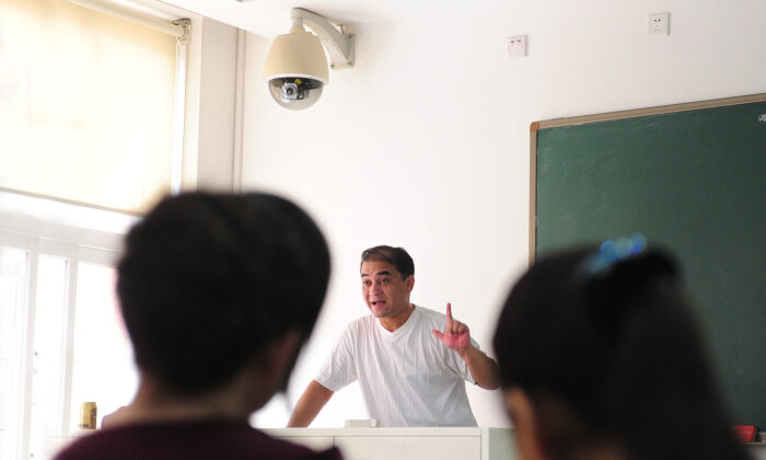 Ilham Tohti, un professeur d'économie ouïghour, donne son cours sous une caméra de surveillance installée au-dessus de l'estrade du professeur dans une salle de classe à Pékin, le 12 juin 2010. Tohti a été condamné à la prison à vie en 2014 pour incitation au séparatisme, et sa famille a perdu tout contact avec lui en 2017. (Frederic J. Brown/AFP via Getty Images)
