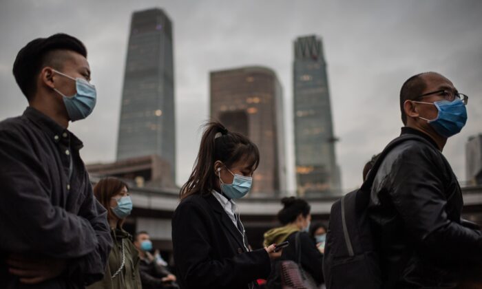 Des Chinois portant des masques faciaux attendent au feu rouge avant de traverser une rue à Pékin, le 14 octobre 2020. (Nicolas Asfouri/AFP via Getty Images)