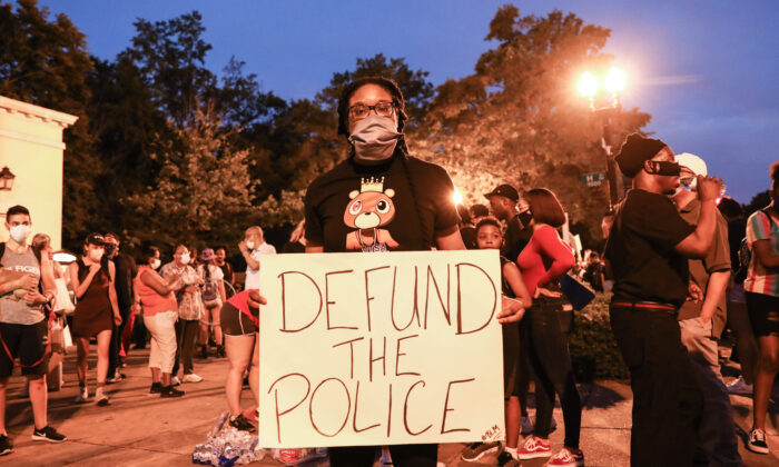 Une manifestante tient une pancarte "Defund the Police" lors d'une manifestation près de la Maison-Blanche à la suite de la mort de George Floyd le 25 mai en garde à vue, à Washington, le 6 juin 2020. (Charlotte Cuthbertson/The Epoch Times)