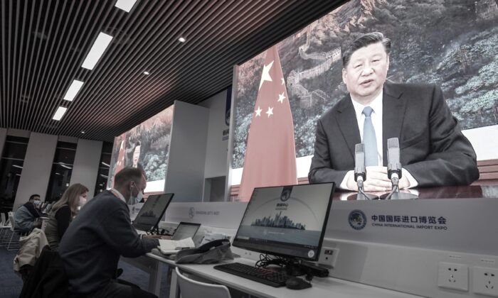 Des journalistes sont assis à côté des écrans montrant le dirigeant chinois Xi Jinping prononçant un discours par vidéo, le 4 novembre 2020. (STR/AFP via Getty Images)
