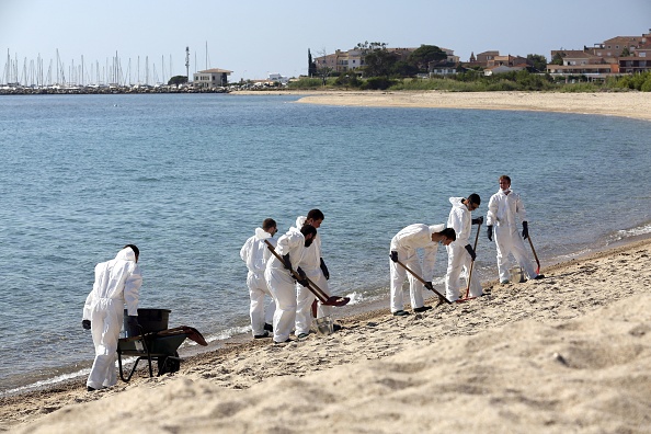 -Des pompiers et des membres de la sécurité civile nettoient la plage de Scaffa Rossa à Solaro le 14 juin 2021,