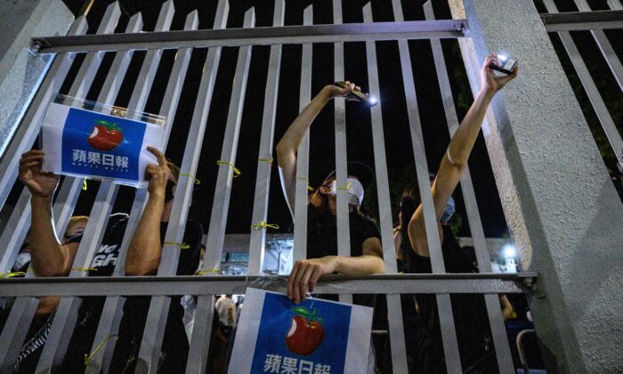 Des partisans se tiennent devant la porte principale des bureaux de l'Apple Daily après l'impression des derniers journaux de l'entreprise dans l'imprimerie de Hong Kong, tôt le 24 juin 2021. (Anthony Wallace/AFP via Getty Images)