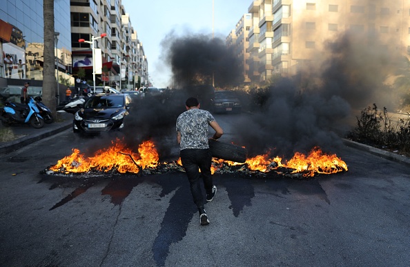 Un Libanais met le feu à des pneus lors d'une manifestation sur une route principale de Beyrouth, la capitale du Liban, pour protester contre les conditions de vie difficiles dans le contexte de la crise économique et politique actuelle, le 28 juin 2021. (Photo : MARWAN TAHTAH/AFP via Getty Images)