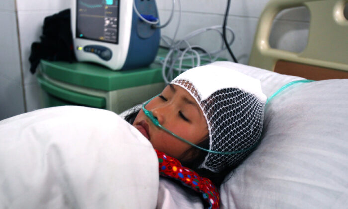 Une fille est allongée sur un lit d'hôpital après avoir été poignardée lors d'une attaque au couteau dans une école primaire du district de Guangshan, dans la province du Henan, en Chine centrale, le 16 décembre 2012. (STR/AFP via Getty Images)