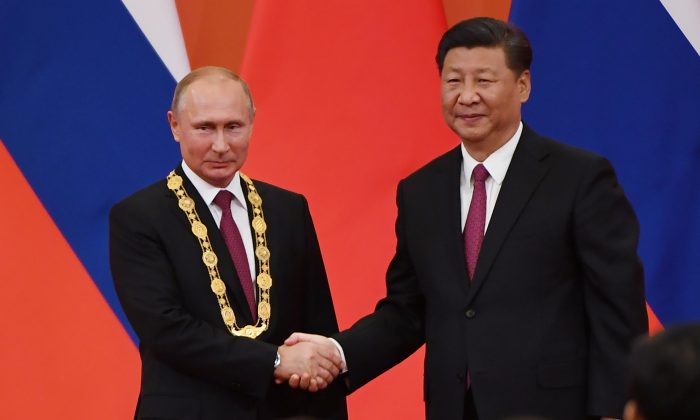 Le chef du Parti communiste et dirigeant chinois Xi Jinping félicite le dirigeant russe Vladimir Poutine après lui avoir remis la médaille de l'amitié dans le Grand palais du Peuple à Pékin, le 8 juin 2018. (Greg Baker/AFP/Getty Images)