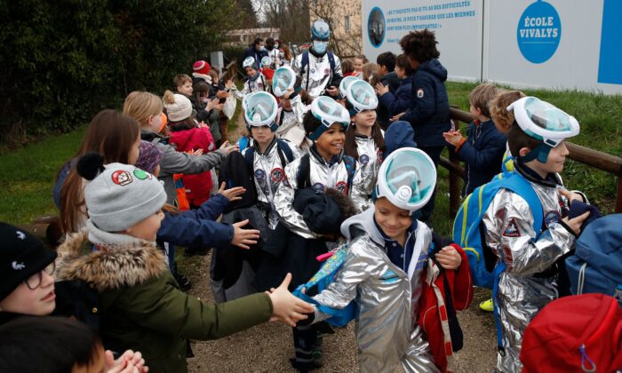 Des enfants serrent la main à des élèves de l'école primaire Vivalys, vêtus de combinaisons spatiales, alors qu'ils quittent l'école au cours de leur projet Mission vers Mars à Lausanne, en Suisse, le 17 mars 2021. (Stefan Wermuth/AFP via Getty Images) 
