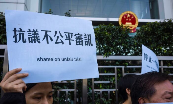 Des militants tiennent des pancartes en soutien à l'avocat chinois des droits de l'homme détenu lors d'un rassemblement devant le bureau de liaison chinois à Hong Kong, le 26 décembre 2018. (Anthony Wallace/AFP via Getty Images)