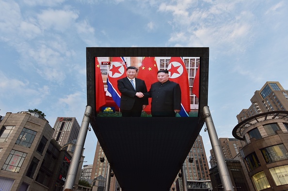 -Des images d'actualités montrant le président chinois Xi Jinping accueilli à Pyongyang par le dirigeant nord-coréen Kim Jong Un, sont montrées sur un grand écran à Pékin le 20 juin 2019. Photo par GREG BAKER / AFP via Getty Images.