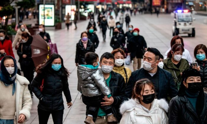 Des Chinois avec des masques marchent dans une rue de Shanghai, en Chine, le 21 février 2020. (NOEL CELIS/AFP via Getty Images)