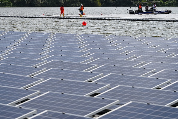Le 3 février 2021 des ouvriers installent des panneaux solaires assemblés pour construire une centrale solaire flottante sur le réservoir de Tengeh à Singapour. Photo de ROSLAN RAHMAN/AFP via Getty Images.