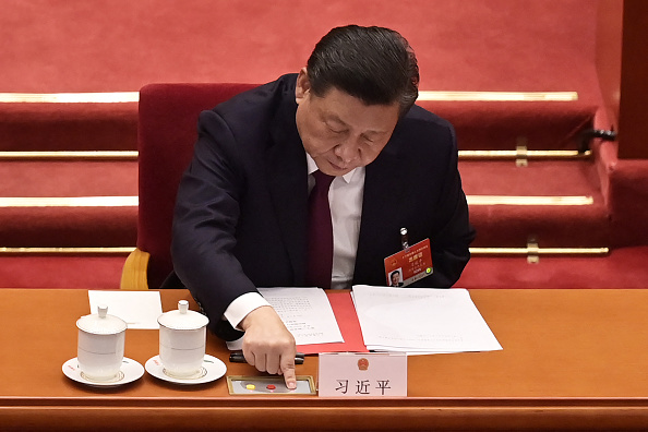 -Le président chinois Xi Jinping vote sur les changements apportés au système électoral de Hong Kong à Pékin le 11 mars 2021. Photo de NICOLAS ASFOURI/AFP via Getty Images.