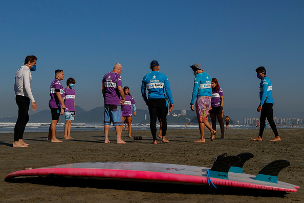 -Les surfeurs brésiliens Miguel Almeida et Malu Mendes prient avant pendant une formation à l'école de surf adaptée de Gonzaga Beach, à Santos, Sao Paulo, Brésil, le 2 juin 2021. Photo Miguel SCHINCARIOL / AFP via Getty Images.