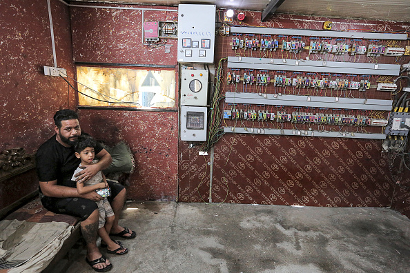 -L'Irakien Aqeel Hassan, l'un des propriétaires de générateurs électriques privés, est photographié avec son fils Muslim, 5 ans, le 17 juillet 2021 dans son entreprise à Bagdad, qui alimente 270 maisons du bloc. Photo de Sabah ARAR / AFP via Getty Images.