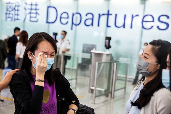 Une femme pleure aux portes d'embarquement de l'aéroport international de Hong Kong avant d'émigrer en Grande-Bretagne le 19 juillet 2021. Photo ISAAC LAWRENCE/AFP via Getty Images.