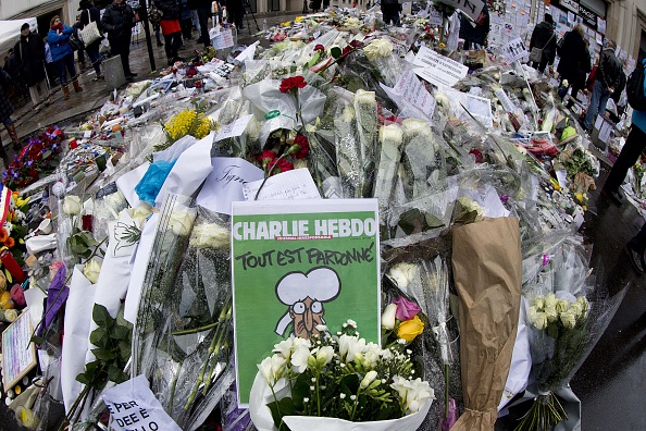 Un exemplaire de la dernière édition du magazine satirique français Charlie Hebdo est placé parmi les hommages floraux déposés devant les bureaux du magazine à Paris, le 14 janvier 2015.        (Photo : JOEL SAGET/AFP via Getty Images)